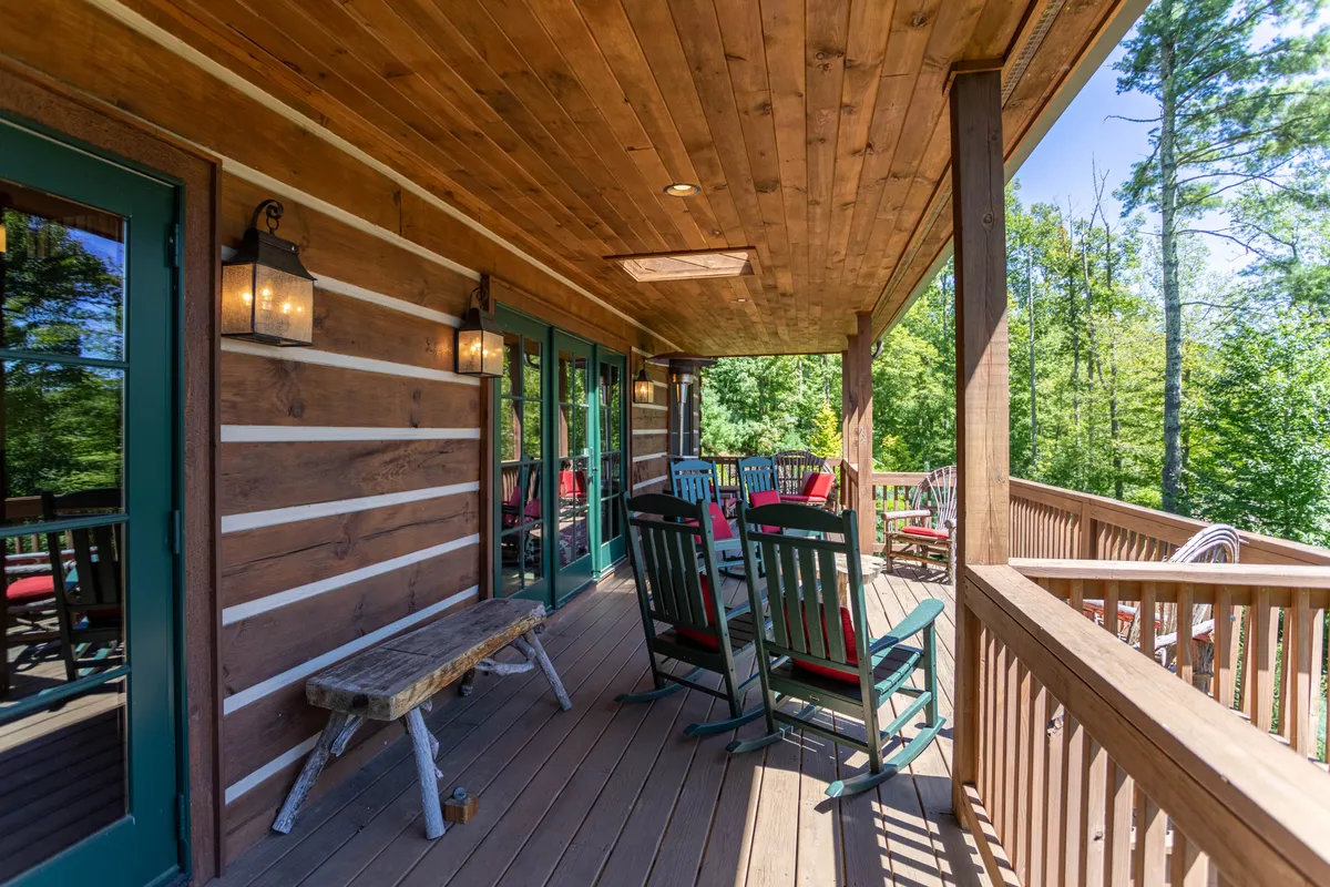 A wooden deck framed by lanterns and rocking chairs, overlooking a peaceful, green landscape. The setup invites guests to relax, socialize, and soak in the natural surroundings, perfect for group conversations or quiet moments between adventures.